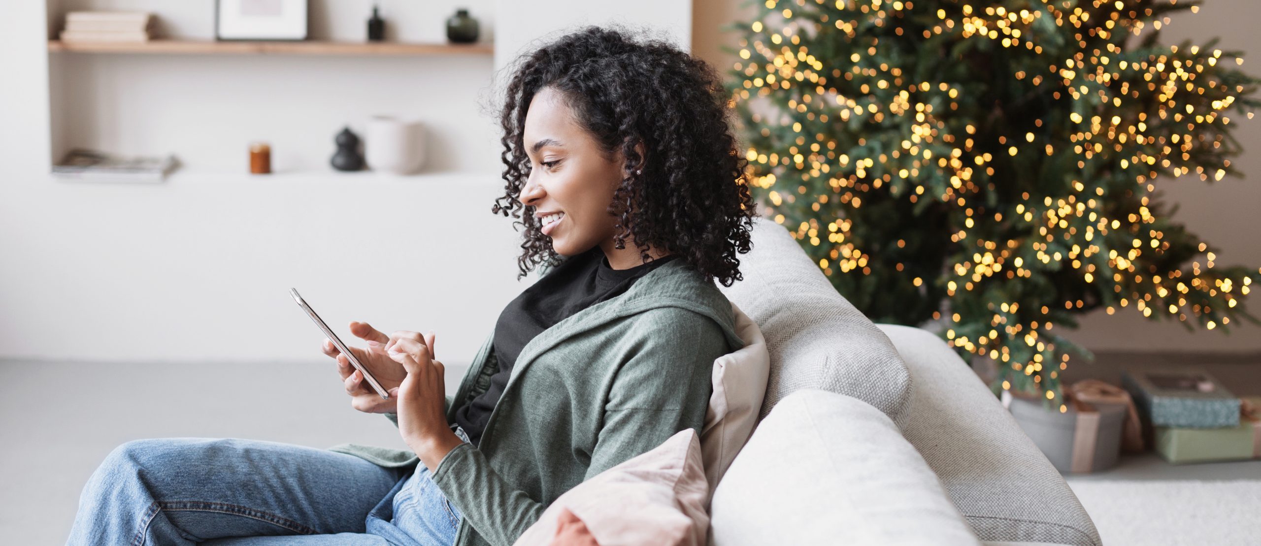 young black woman texting on couch at christmas